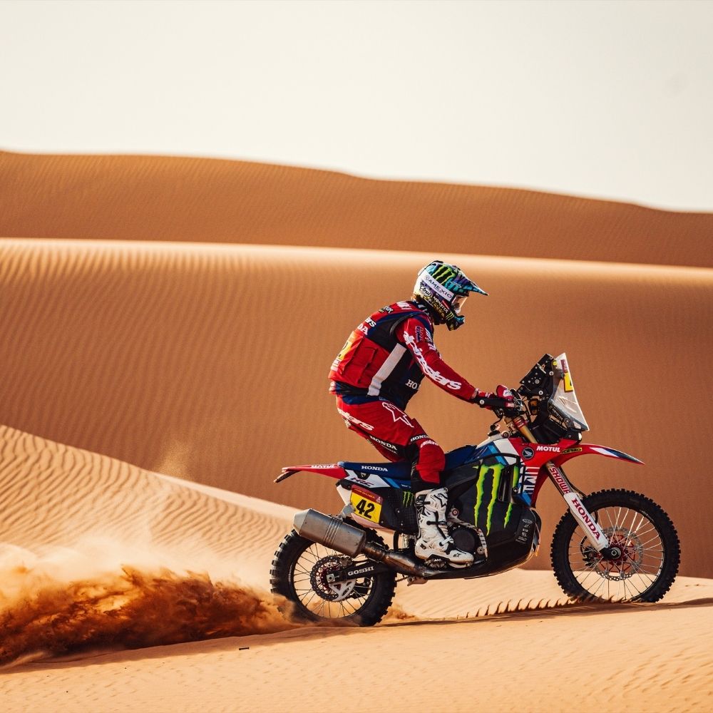 Adrien Van Beveren à moto dans le désert d’Abu Dhabi lors d’un rallye-raid international, casque porté en conditions extrêmes.